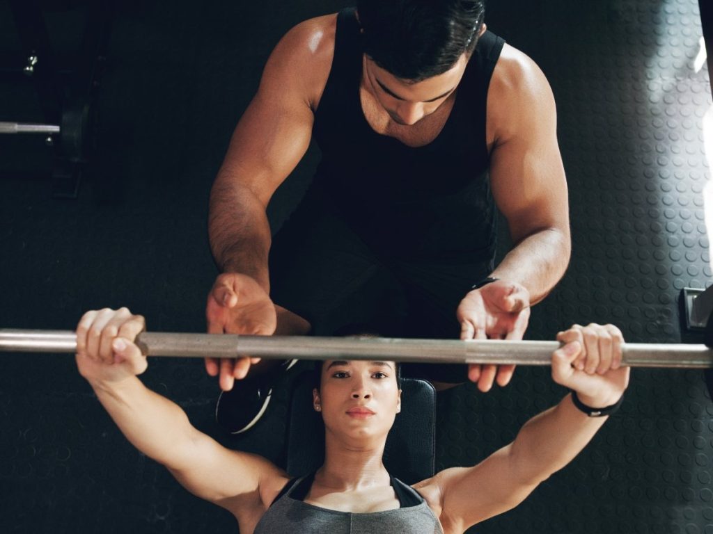 Contar con un acompañante capacitado durante el press de banca puede marcar la diferencia entre un entrenamiento seguro y un accidente grave.