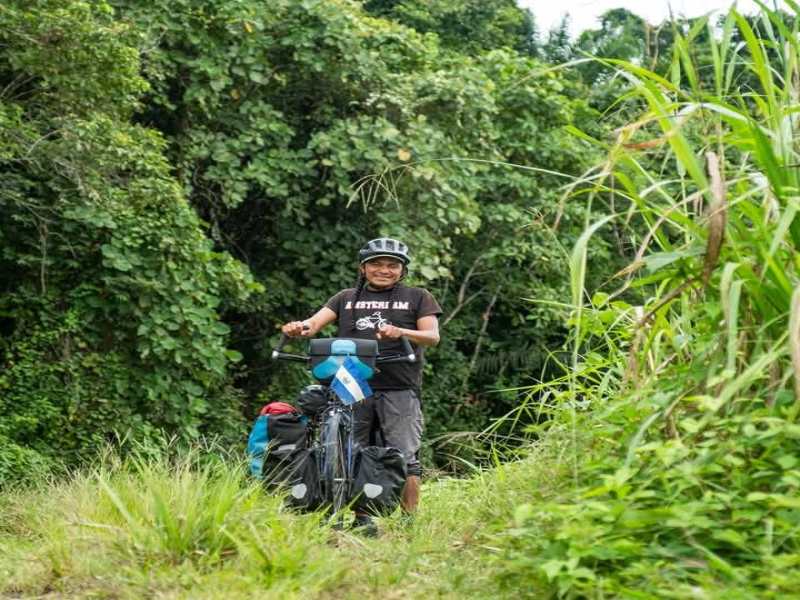 Ruiz se muestra sonriente junto a su bicicleta en una pausa del viaje, tras superar miles de kilómetros de rutas urbanas y caminos rústicos.