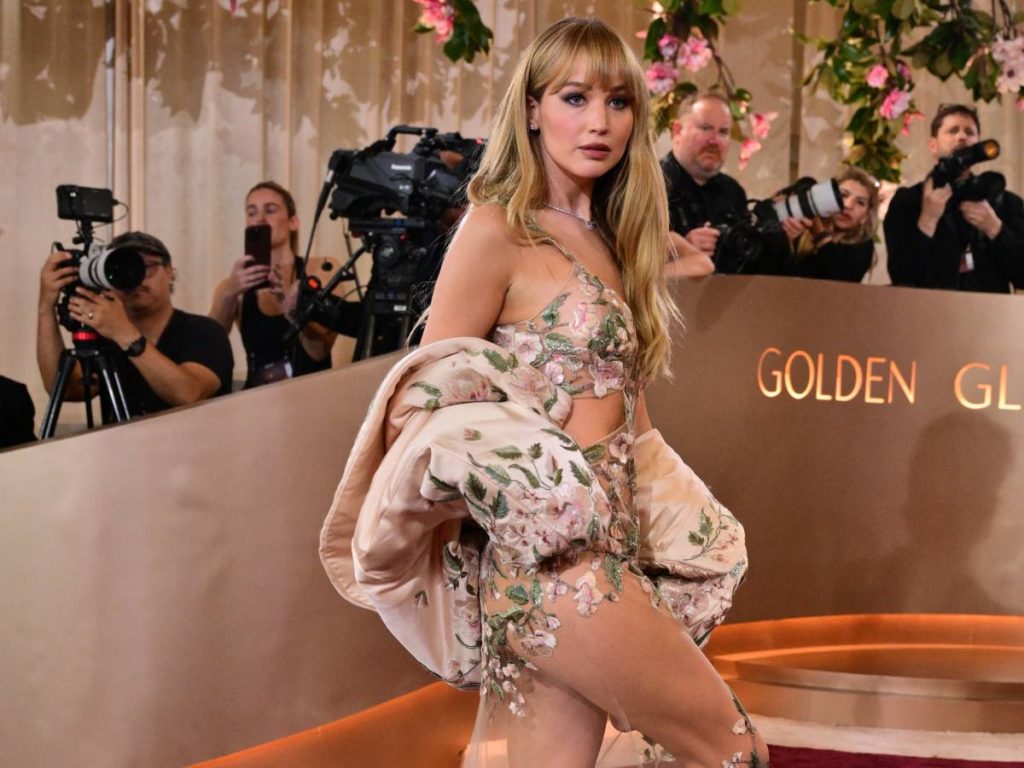 Jennifer Lawrence apostó por las transparencias con un vestido de Givenchy diseñado por Sarah Burton, acompañado por ondas suaves, smokey eyes azul, labios rojo fresa. /