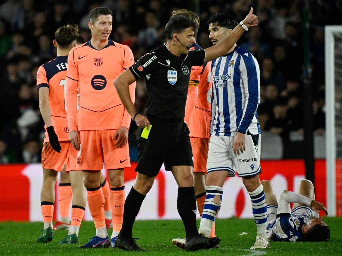 El árbitro español Jesús Gil hace un gesto tras mostrar una tarjeta amarilla al delantero polaco #09 del Barcelona, ​​Robert Lewandowski, durante el partido de fútbol de la liga española entre la Real Sociedad y el FC Barcelona en el Estadio de Anoeta en San Sebastián. AFP
