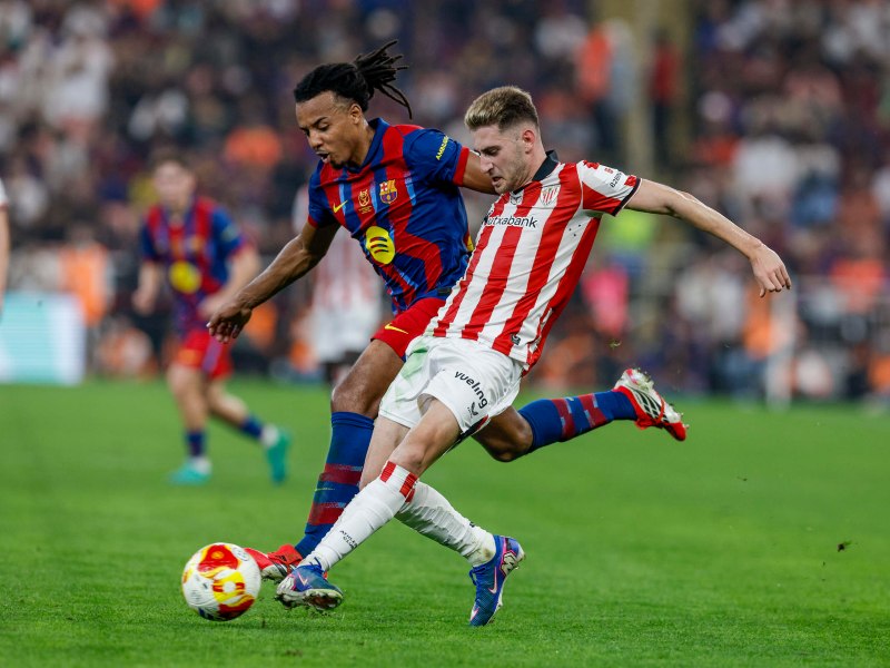 El defensor francés del Barcelona, #23 Jules Koundé, disputa el balón con el delantero español del Athletic Bilbao, #23 Robert Navarro, durante el partido de semifinales de la Supercopa de España entre el FC Barcelona y el Athletic Bilbao, disputado en el King Abdullah Sports City, en Yeda, el 7 de enero de 2026. / AFP