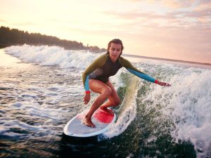Niños participan en clases gratuitas de surf como parte de la agenda Wellness & Friends en la costa de Surf City.