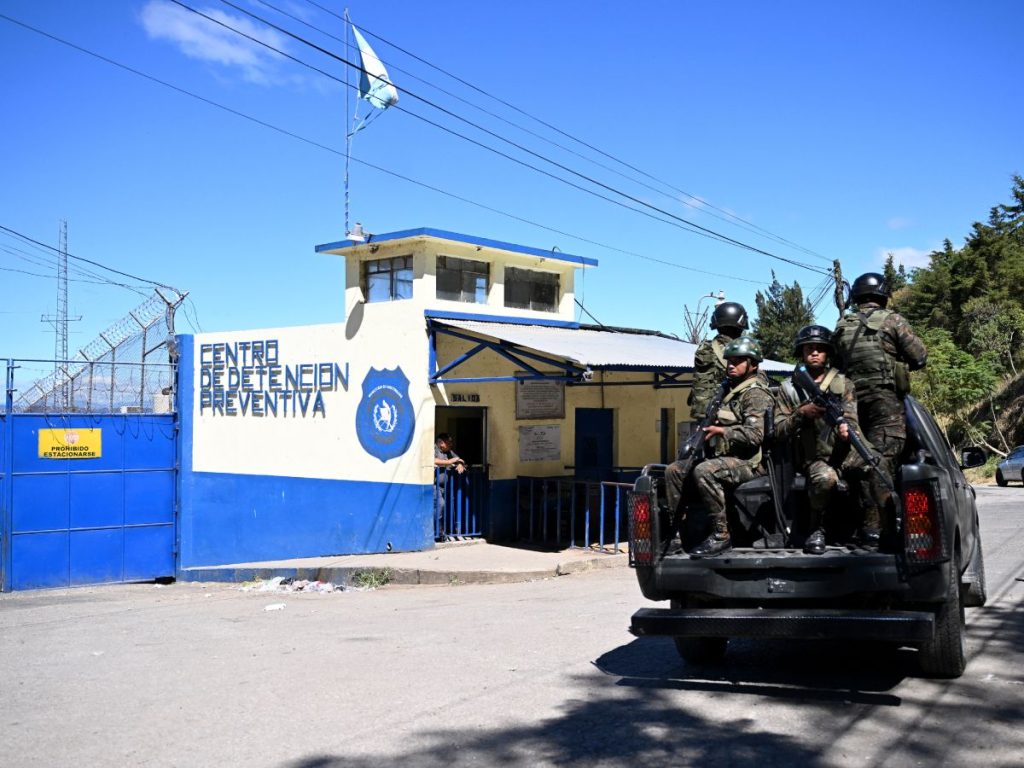 Soldados guatemaltecos a bordo de un vehículo pasan frente a la entrada del Centro Preventivo para Hombres, en Ciudad de Guatemala, el 21 de enero de 2026, durante el estado de emergencia decretado por el Gobierno nacional. Fotografía/ AFP