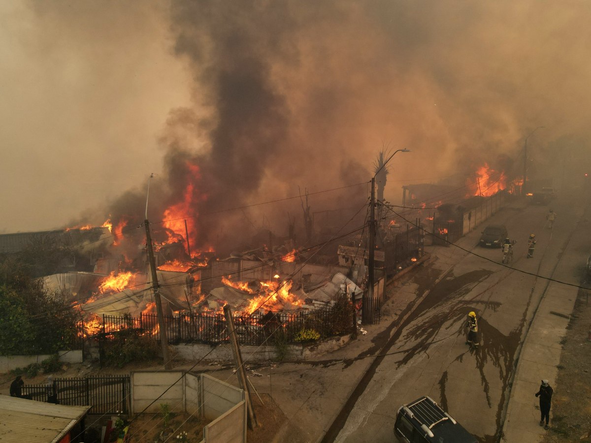 En esta vista aérea, humo y llamas se elevan desde viviendas en llamas durante un incendio forestal en Concepción, Chile, el 18 de enero de 2026. Fotografía/ AFP