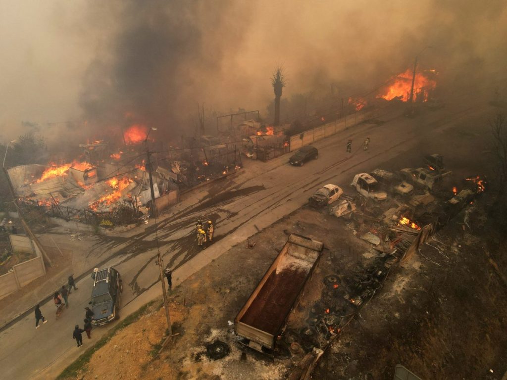 En esta vista aérea, humo y llamas se elevan desde viviendas en llamas durante un incendio forestal en Concepción, Chile, el 18 de enero de 2026. Fotografía/ AFP