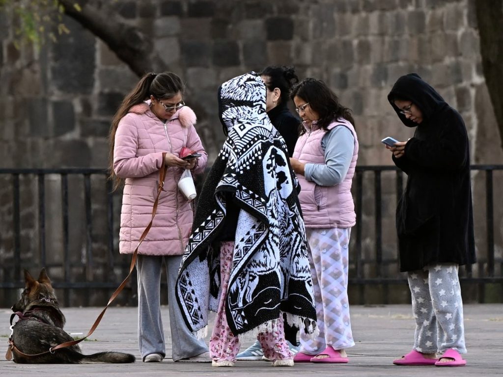 Mujeres en pijama permanecen afuera tras evacuar sus viviendas durante un sismo de magnitud 6.5 en Ciudad de México, el 2 de enero de 2026. Fotografía/AFP