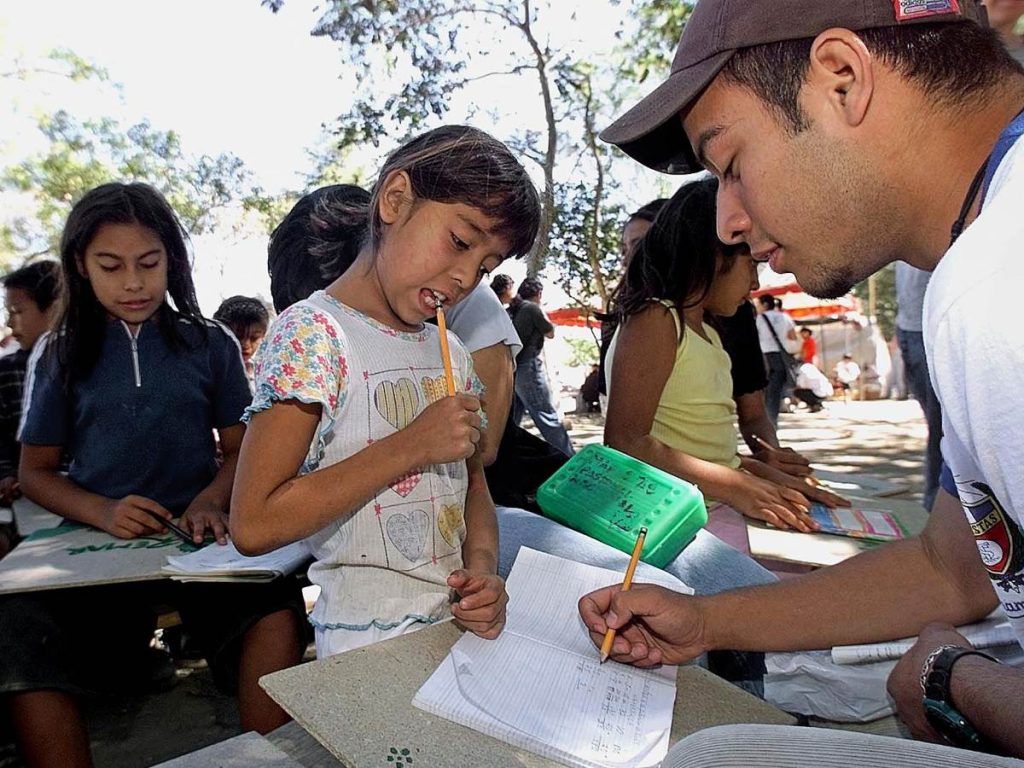 Un profesor voluntario instruye el 6 de febrero de 2001 a una niña damnificada por el terremoto del 13 de enero, durante una clase de matemáticas al aire libre en el campo para damnificados El Cafetalón, en Santa Tecla, El Salvador.