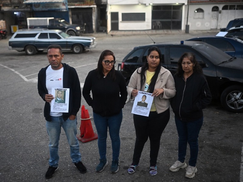 Familiares de reclusos sostienen carteles de sus seres queridos, afuera de la prisión El Rodeo I en Guatire, estado Miranda, a unos 30 kilómetros al este de Caracas, el 12 de enero de 2026.