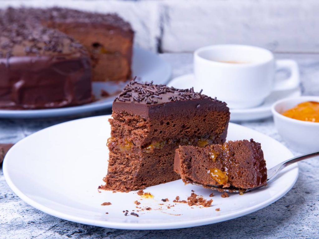 Delicada Sachertorte con glaseado brillante y relleno de mermelada de albaricoque. Elegancia vienesa en cada bocado.