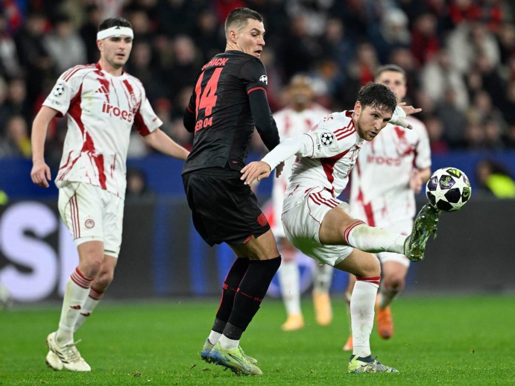 El delantero checo #14 del Bayer Leverkusen, Patrik Schick (centro), y el defensa griego #45 del Olympiakos, Panagiotis Retsos (derecha), disputan el balón durante el partido de vuelta de los play-offs de la UEFA Champions League entre el Bayer 04 Leverkusen y el Olympiakos 