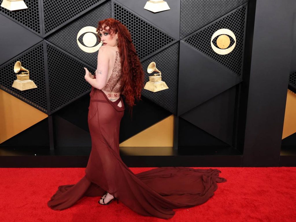 Chappell Roan juega con transparencias vino tinto y espalda tatuada como eje del look, una mezcla de sensualidad noventera y teatralidad controlada que no pasa inadvertida.