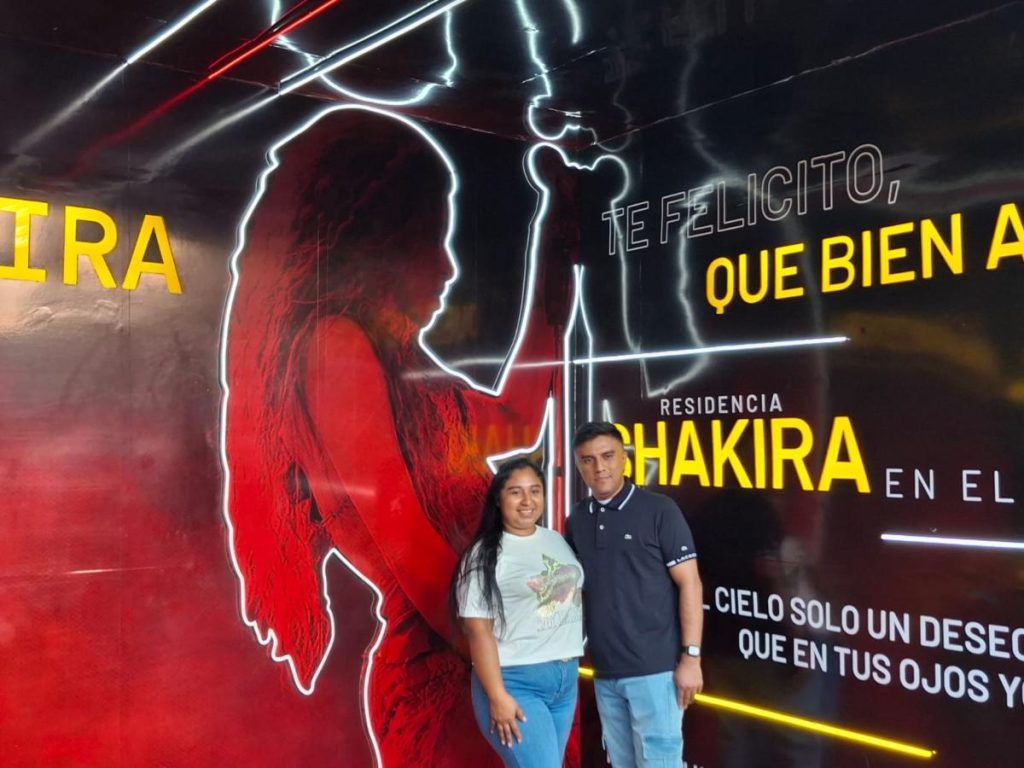 Una pareja posa frente a un mural iluminado de Shakira en los alrededores del Estadio Mágico González, previo al concierto de la artista en El Salvador.