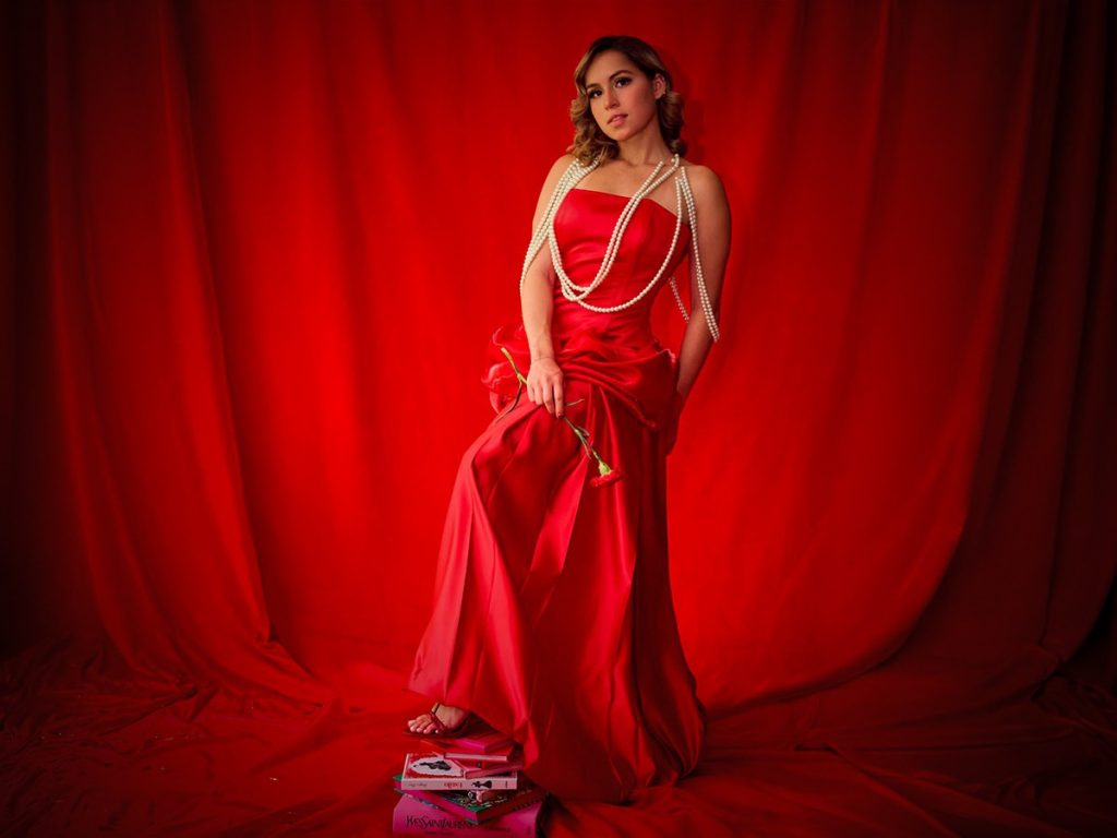 Vestido rojo escarlata de la diseñadora emergente Mónica Rodríguez Morales. Corset strapless, falda amplia y drapeado escultórico en la cadera construyen una silueta elegante y poderosa. Collares de Patricia de Ábrego.