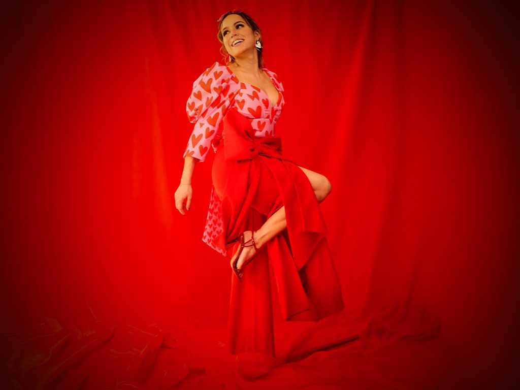 Look total de Andrea Ayala. Corazones gráficos, volumen en las mangas y un lazo protagonista construyen una silueta femenina, lúdica y sensual que celebra el amor desde el movimiento. 