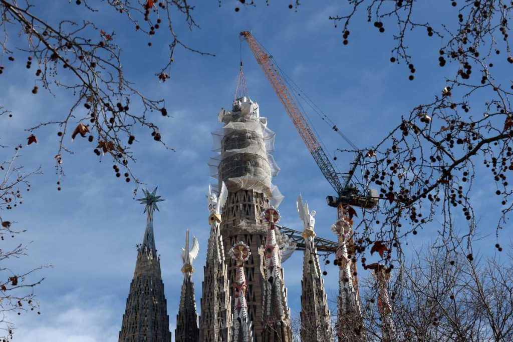 Una grúa levanta la última pieza de la cruz de 17 metros de alto y 13,5 metros de ancho que completa la Torre de Jesucristo de la Sagrada Familia en Barcelona el 20 de febrero de 2026.
