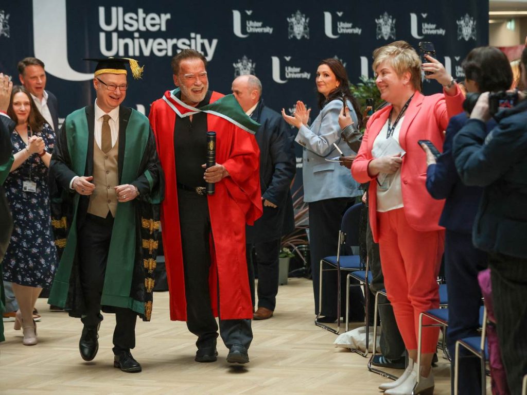 Arnold Schwarzenegger camina junto al rector Paul Bartholomew tras recibir un doctorado honoris causa de la Universidad del Ulster en Belfast, el 30 de marzo de 2026. 
