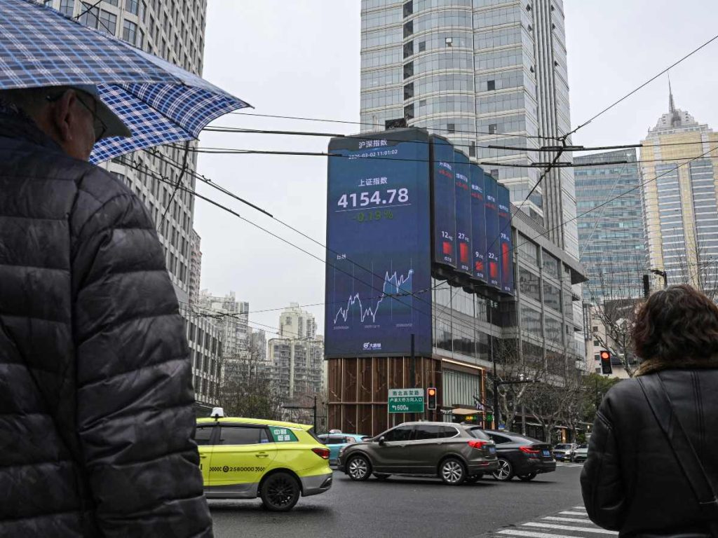 Peatones frente a una pantalla con el índice de Shanghái en Jing’an, el 2 de marzo de 2026, en una jornada marcada por la caída bursátil y el alza del petróleo.