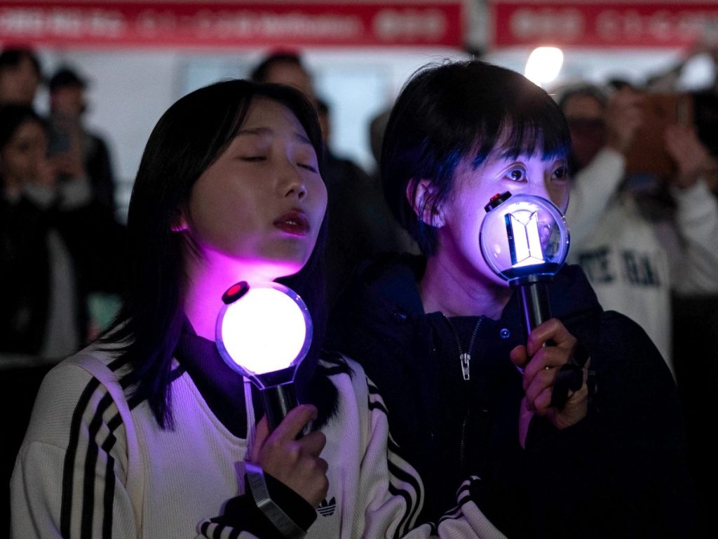 Los fans reaccionan mientras ven el concierto de regreso del grupo masculino de K-pop BTS en una pantalla en el recinto de Seúl el 21 de marzo de 2026.