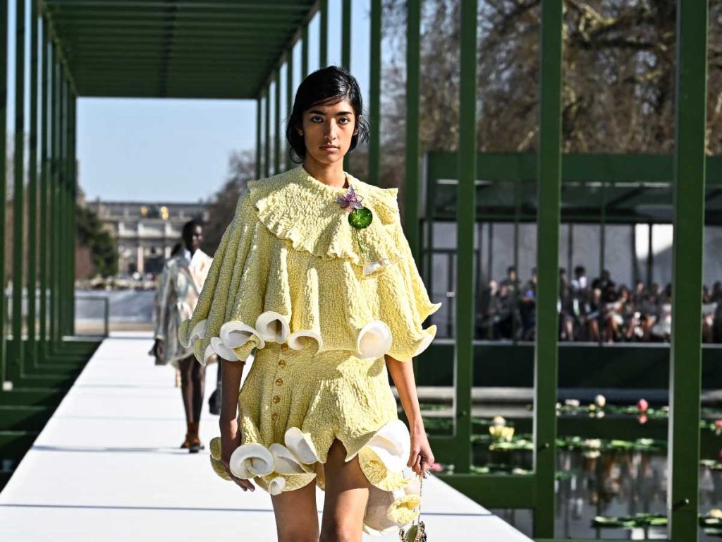 Modelo presenta un vestido amarillo con capas y aplicaciones florales en la pasarela de Dior durante la Semana de la Moda de París, en el jardín de las Tullerías.