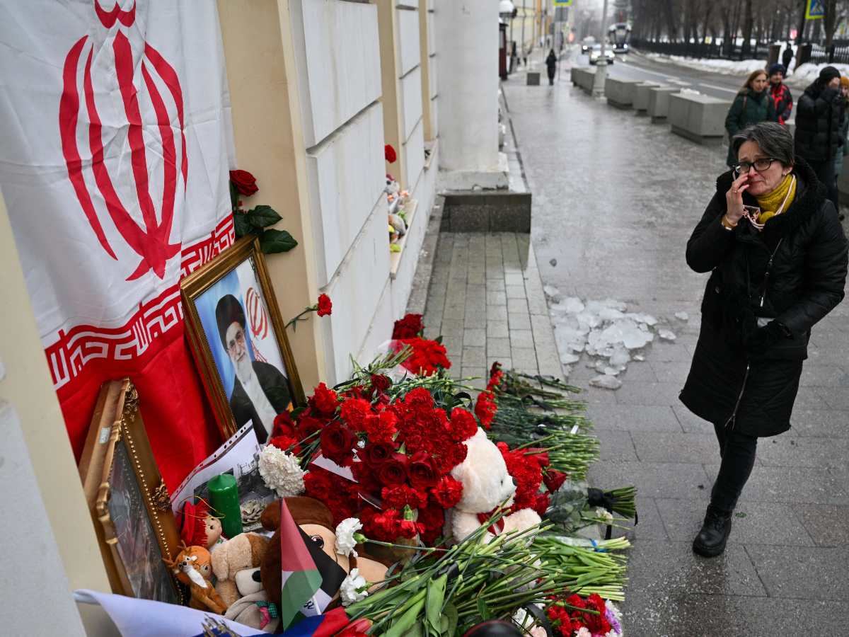 La gente deposita flores en un altar improvisado con un retrato del difunto líder supremo de Irán, el ayatolá Alí Jamenei, y una bandera de la República Islámica de Irán, frente a la embajada de Irán en Rusia, en Moscú, el 2 de marzo de 2026.