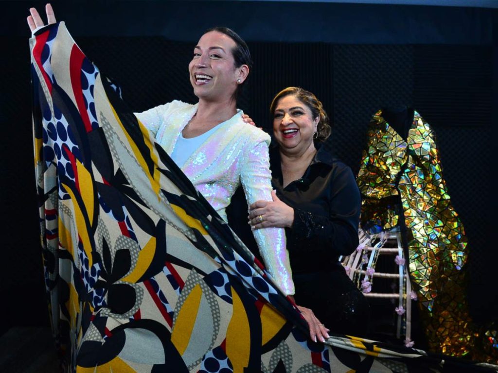 Nory Flores y Rossemberg Rivas comparten un momento espontáneo entre risas y telas, reflejando la complicidad detrás del vestuario para Coachella 2026.