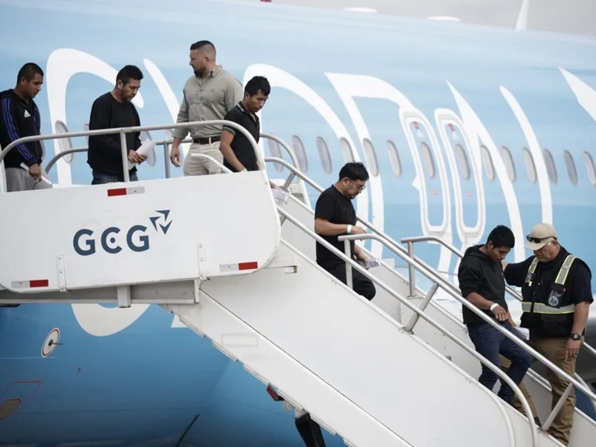 Fotografía de migrantes de distintas nacionalidades, procedentes de Estados Unidos, descienden de un avión este sábado, en el Aeropuerto Internacional Juan Santamaría, en San José (Costa Rica).