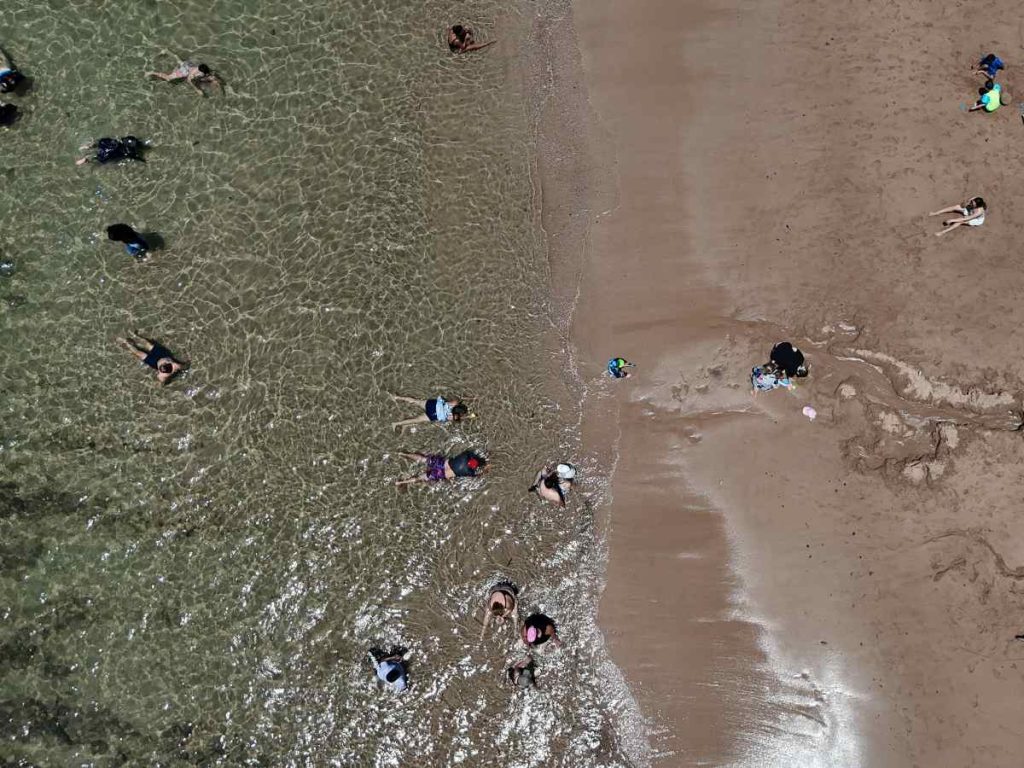 Desde arriba, el agua clara deja ver el fondo y refuerza la experiencia segura que crea el arrecife natural en Playa Los Almendros.