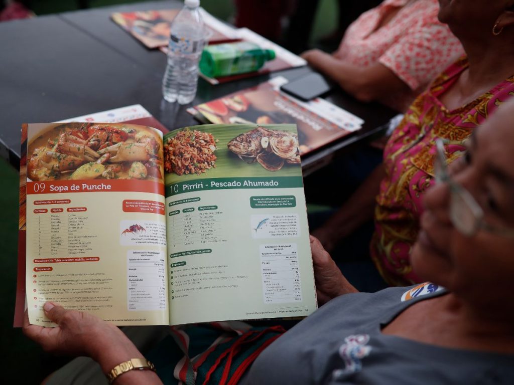 Una mujer observa un recetario del proyecto de seguridad alimentaria Manos que Alimentan este martes, en San Salvador (El Salvador).  EFE