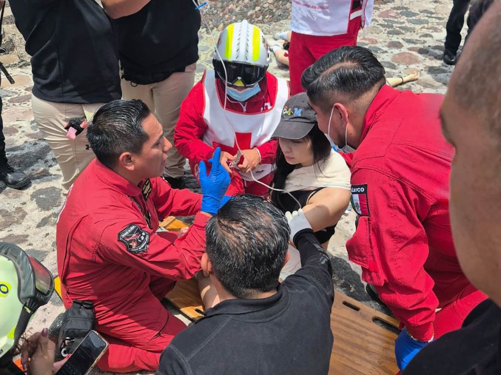 Esta fotografía distribuida por la Cruz Roja Mexicana muestra a paramédicos de la Cruz Roja Mexicana atendiendo a una turista herida en la Pirámide de la Luna, en la zona arqueológica de Teotihuacán, tras un tiroteo ocurrido en Teotihuacán, Estado de México, el 20 de abril de 2026.