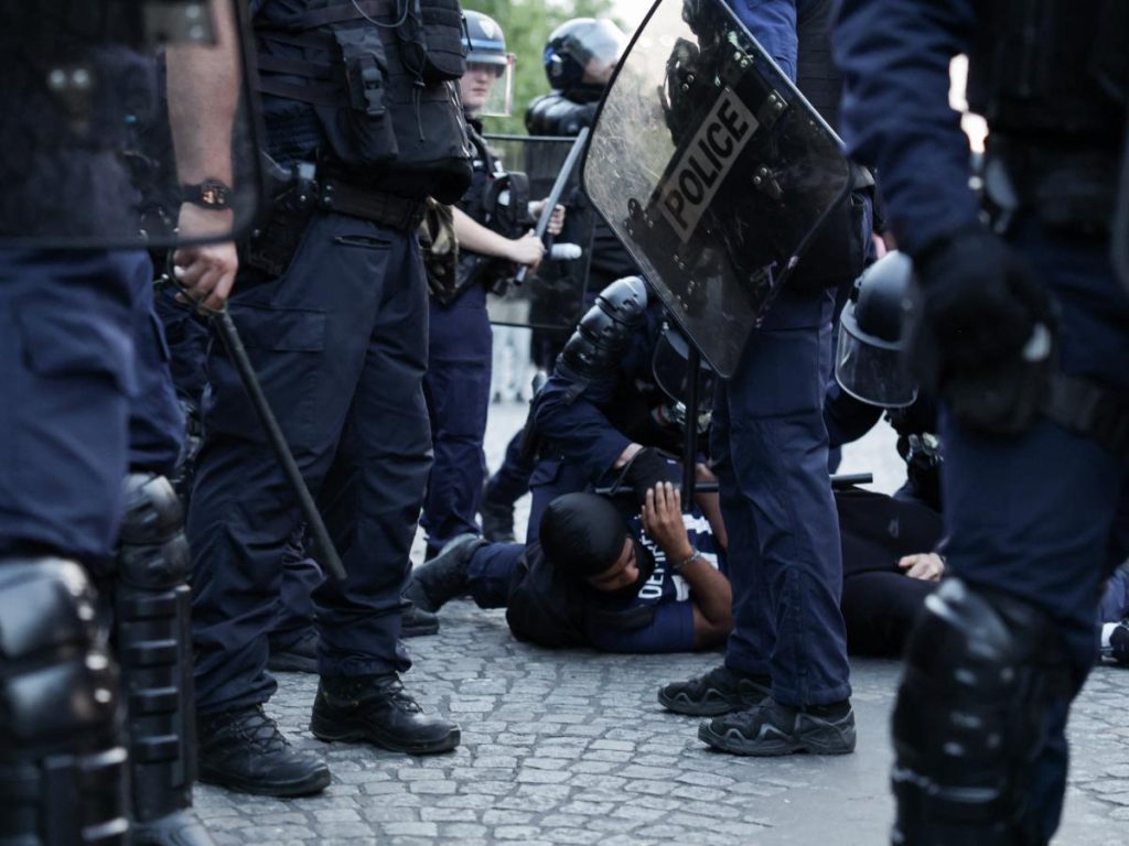 Agentes del CRS detienen a un seguidor del PSG durante las celebraciones en los Campos Elíseos.