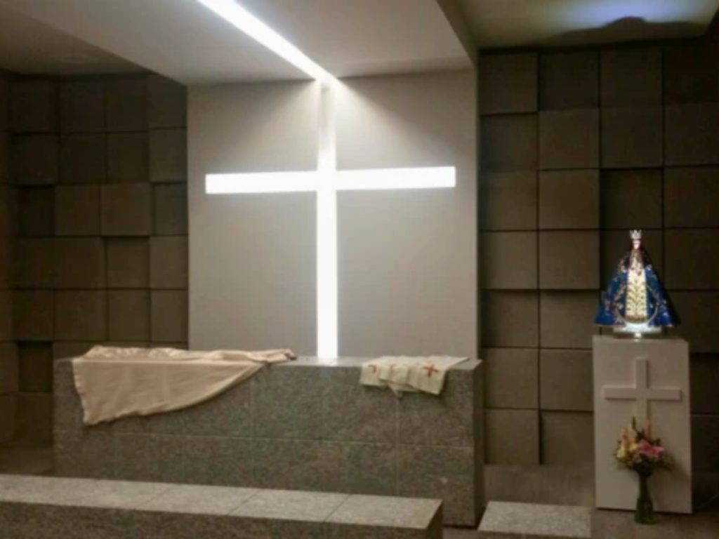 Capilla del Estadio Monterrey, con una cruz iluminada y una imagen de la Virgen del Roble junto al altar.