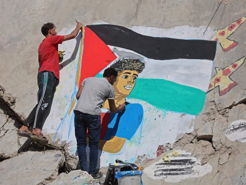 Artistas palestinos pintan un mural que representa al futbolista Lamine Yamal ondeando una bandera palestina durante el desfile de celebración del título del Catalán, sobre los escombros de edificios destruidos durante la guerra, en el campamento de refugiados de Shati (Playa) en la ciudad de Gaza el 13 de mayo de 2026.
