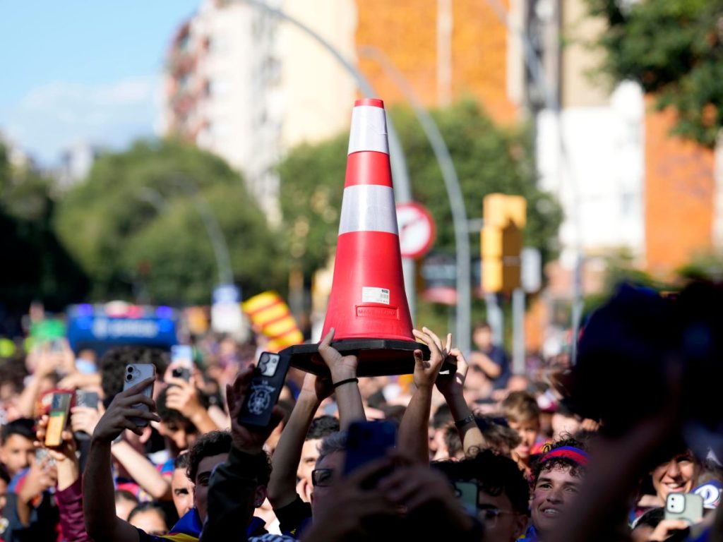 Aficionados exhiben un cono al paso de los jugadores del FC Barcelona durante la rúa con la que el equipo azulgrana festeja con su afición la consecución del título de campeón de LaLiga. EFE