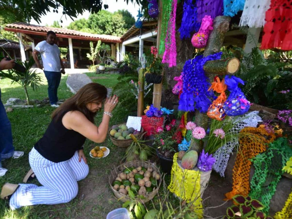 Altar del restaurante Ciudad Vieja en Suchitoto, donde visitantes se arrodillan, hacen la señal de la cruz y toman una fruta como acto de fe y tradición.
