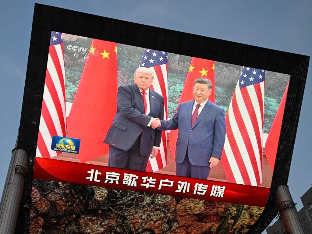 Una gran pantalla muestra la retransmisión del encuentro entre el presidente chino Xi Jinping y el presidente estadounidense Donald Trump en el Gran Salón del Pueblo en Pekín, el 14 de mayo de 2026. (Foto de WANG Zhao / AFP)

