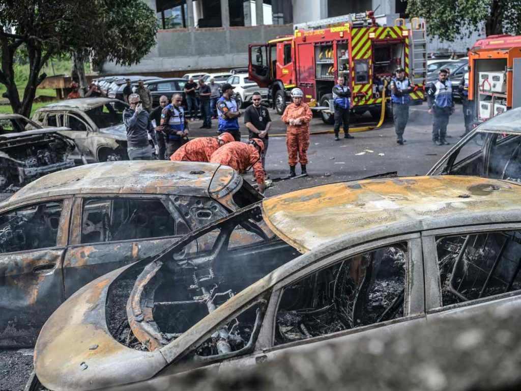 Bomberos y policías trabajan junto a vehículos calcinados tras el accidente de dos helicópteros en Río de Janeiro. 