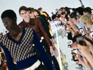 Invitados usan sus celulares durante el cierre del desfile masculino primavera-verano 2027 de Prada en la Semana de la Moda de Milán.