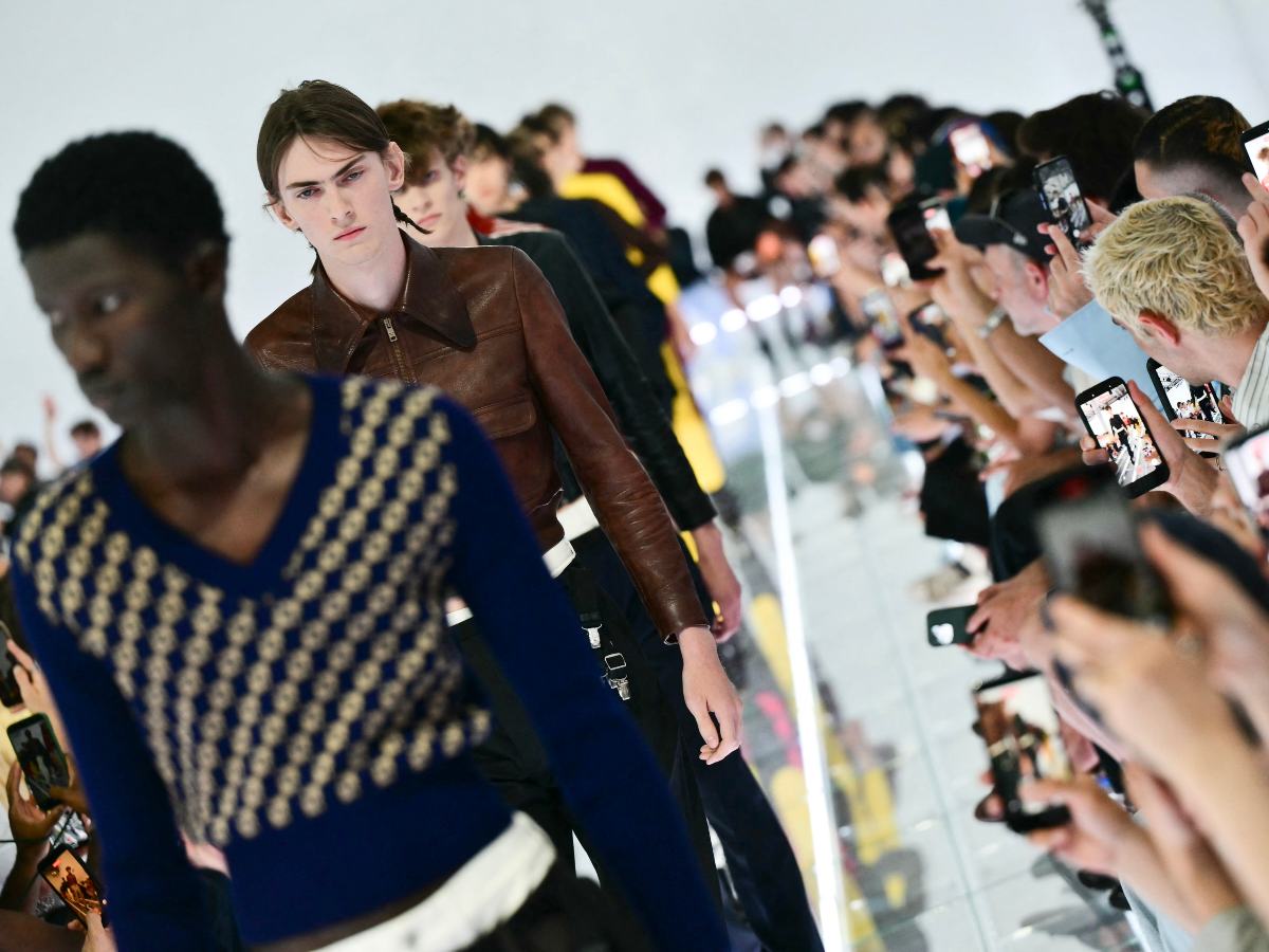 Invitados usan sus celulares durante el cierre del desfile masculino primavera-verano 2027 de Prada en la Semana de la Moda de Milán.