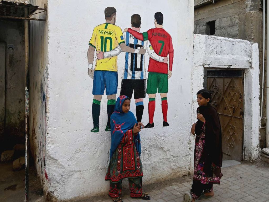 Unas niñas pasan junto a un mural con las figuras de los futbolistas Neymar (Brasil), Lionel Messi (Argentina) y Cristiano Ronaldo (Portugal), en vísperas de la Copa Mundial de la FIFA 2026. 
