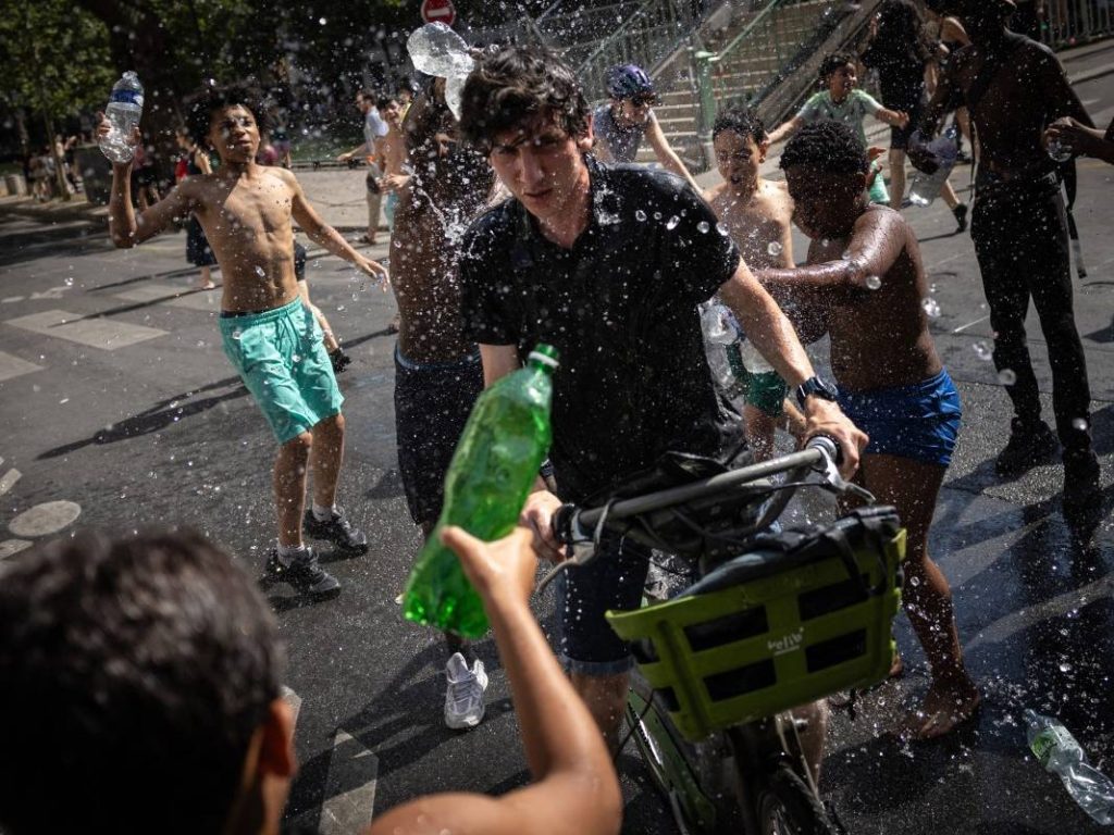 Un grupo de adolescentes arroja agua a unos ciclistas junto al Canal Saint-Martin durante una ola de calor en París, el 24 de junio de 2026. Francia experimentó el día más caluroso jamás registrado ese día, superando el récord del día anterior, según el servicio meteorológico nacional Meteo-France. Foto AFP
