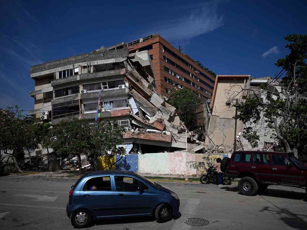 Un automóvil circula frente a edificios derrumbados en Catia La Mar, Venezuela, tras el terremoto del 25 de junio de 2026. Foto: Federico Parra/AFP.