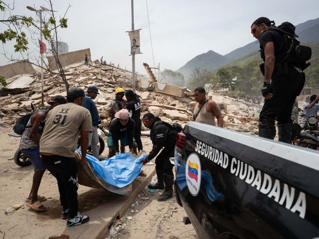 Voluntarios rescatan una víctima mortal este jueves, entre los escombros de edificios afectados por los terremotos en La Guaira (Venezuela). 