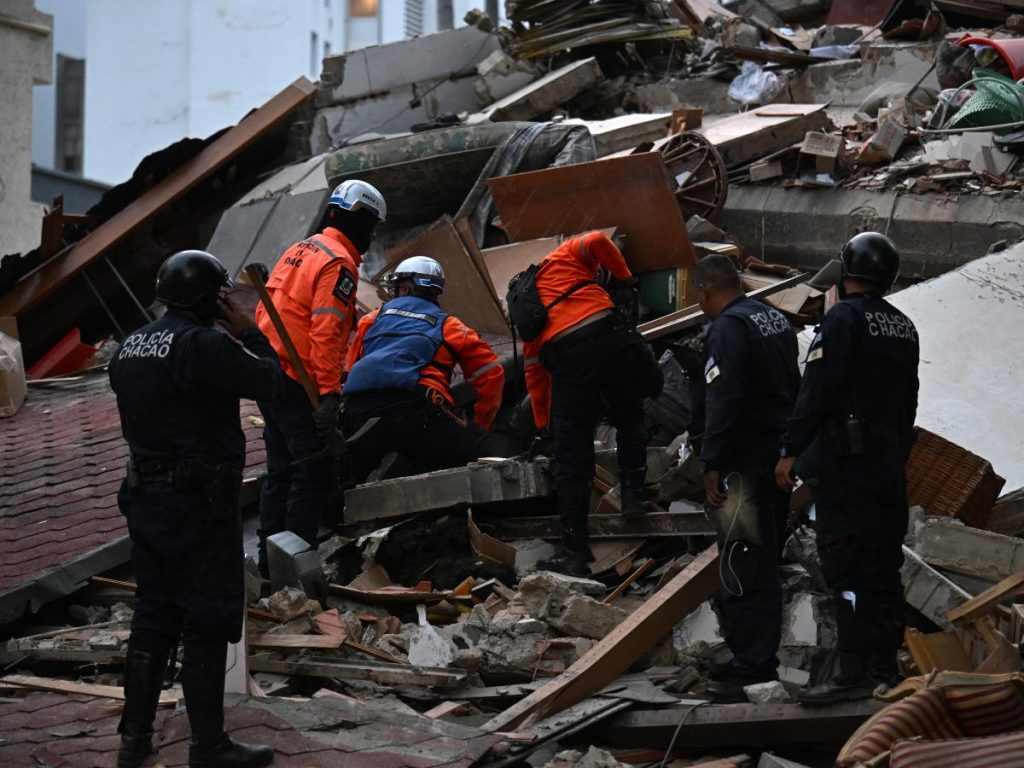 Los rescatistas buscan entre los restos de una estructura derrumbada mientras agentes de la policía municipal permanecen cerca tras el terremoto que sacudió Caracas el 24 de junio de 2026.
