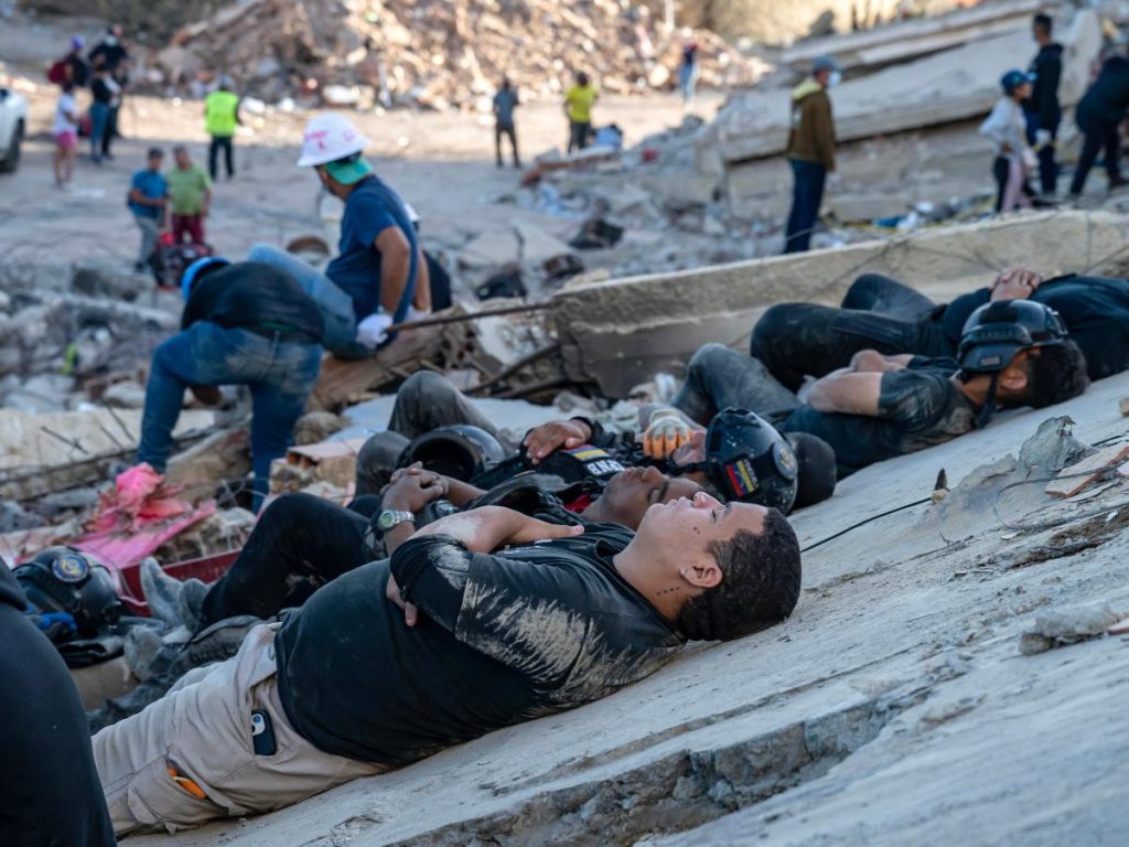 Rescatistas y voluntarios descansan sobre los escombros de edificios derrumbados en Caraballeda, estado de La Guaira, Venezuela, el 28 de junio de 2026, tras los terremotos.
