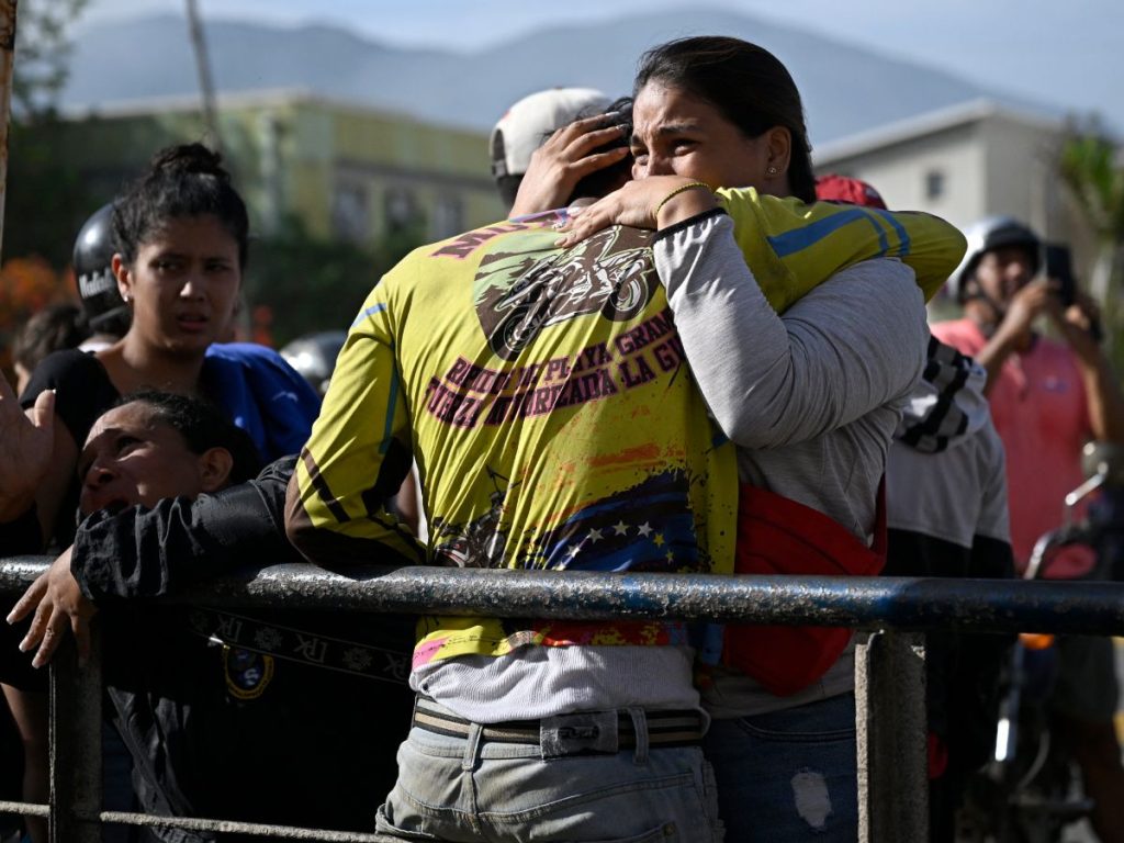 Residentes de Catia la Mar se consuelan mientras continúan las labores de búsqueda de desaparecidos. Foto AFP.