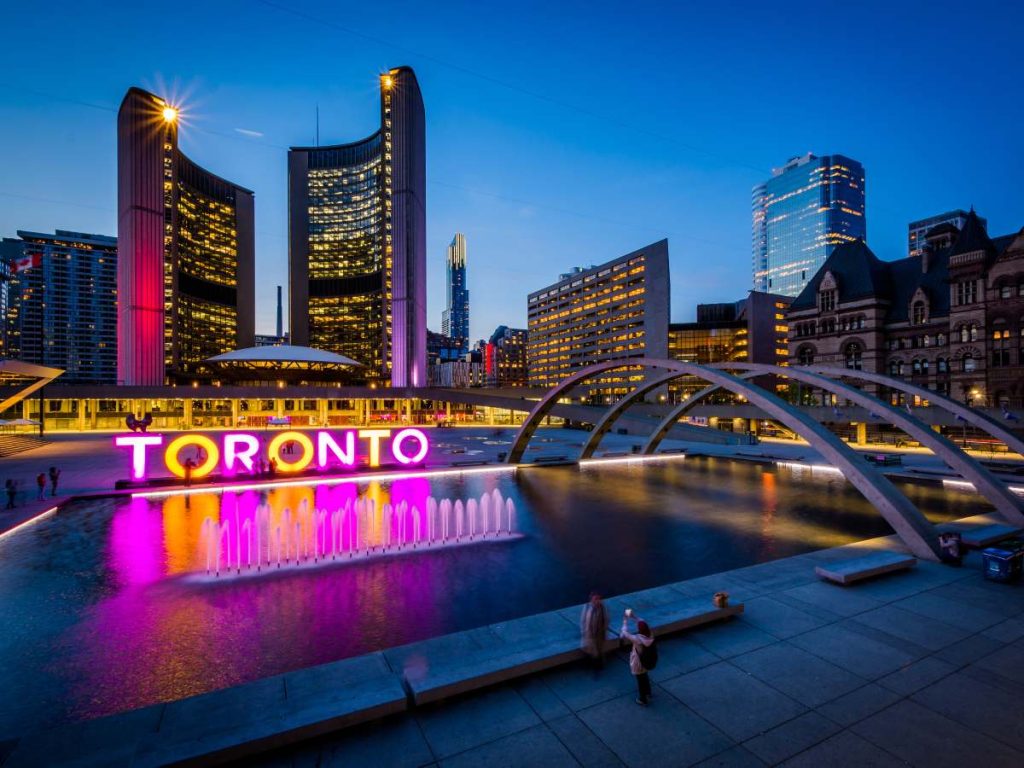 Plaza Nathan Phillips y la bandera de Toronto al crepúsculo, en el corazón del centro urbano de la ciudad canadiense.
