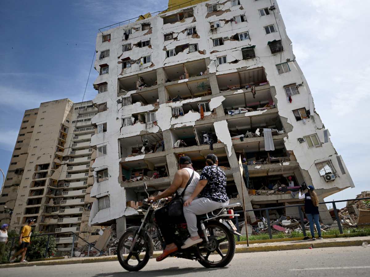 Dos personas pasan en motocicleta frente a un edificio dañado por el terremoto en Catia La Mar, Venezuela.
