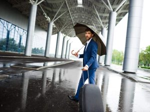 Picture of  young  businessman holding  suitcase and umbrella walking in rain