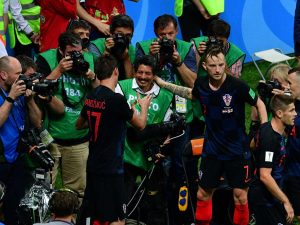 El delantero croata Mario Mandzukic (izquierda) estrecha la mano del fotógrafo de AFP Yuri Cortez después de caer sobre él junto a sus compañeros mientras celebraban el segundo gol de Croacia durante la semifinal del Mundial Rusia 2018 entre Croacia e Inglaterra en Moscú, el 11 de julio de 2018. Fotografía/ AFP