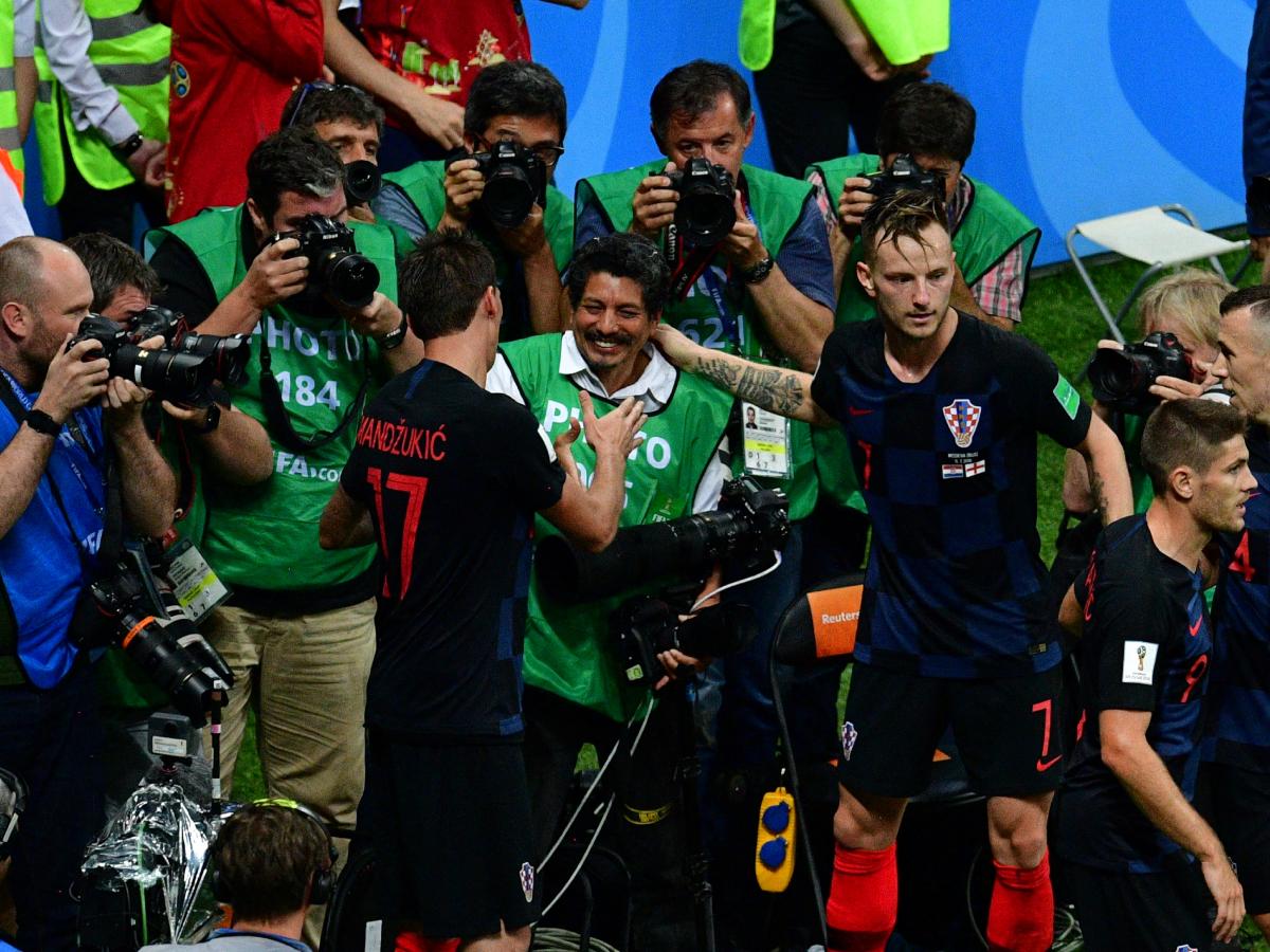 El delantero croata Mario Mandzukic (izquierda) estrecha la mano del fotógrafo de AFP Yuri Cortez después de caer sobre él junto a sus compañeros mientras celebraban el segundo gol de Croacia durante la semifinal del Mundial Rusia 2018 entre Croacia e Inglaterra en Moscú, el 11 de julio de 2018. Fotografía/ AFP